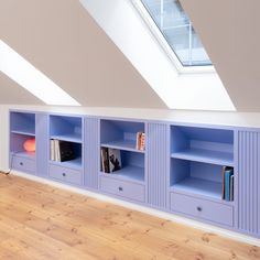 blue bookcases in the corner of a room with wooden floors and skylight