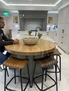 a man sitting at a kitchen table with two stools in front of him and a bowl on the center island