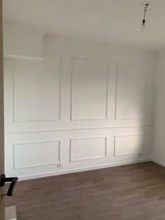 an empty room with white walls and wood floors