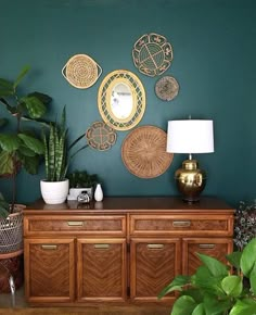 a living room with green walls and plants on the sideboard in front of it