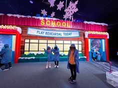 three people standing in front of a school with snowflakes on the roof and windows