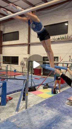 a person on a pole doing tricks in an indoor gymnastics court with other people watching