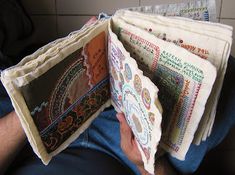 a man is sitting down and holding some cloths in his hands with the pages folded open