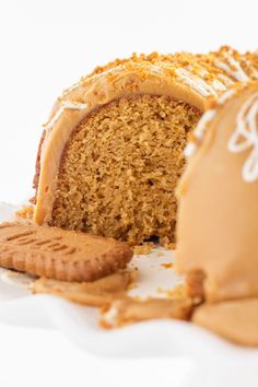 a piece of cake with frosting next to a cookie on a white tablecloth