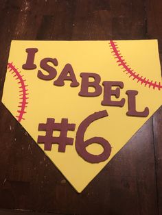 a close up of a baseball shaped sign on a wooden table with the number six