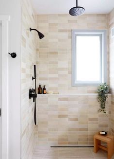 a bathroom with a window, shower head, and bench next to the bathtub