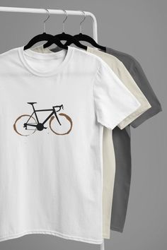 This would be a lovely gift for any cyclist! -  Coffee mug rings bicycle t-shirt. This t-shirt feels soft and lightweight, with the right amount of stretch.  t's comfortable and flattering for both men and women.  * 100% combed and ring-spun cotton (heather colours contain polyester) * Fabric weight: 4.2 oz (142 g/m2) * Pre-shrunk fabric * Shoulder-to-shoulder taping * Side-seamed Other colours available, contact us for more details. Care instructions   Machine wash: warm (max 40C or 105F) Non-c White Graphic Print T-shirt For Cycling, Cycling T Shirts, Bike Gift, Cycling Gifts, Cycling T-shirt, T-shirt Refashion, Rainy Day Outfit, Gifts Birthday, Cut Tshirt