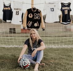 a woman sitting on the ground next to a soccer ball in front of a goal