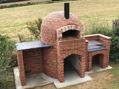 an outdoor brick pizza oven sitting on top of a cement slab next to a field