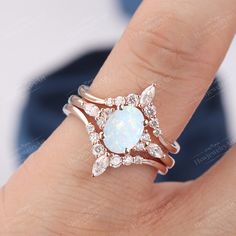 a woman's hand holding a ring with an oval blue stone surrounded by diamonds