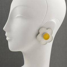 Gorgeous oversized frosted lucite clip-on earrings designed by Harriet Bauknight for Kaso. Dimensional shape all carved and textured featuring a daisy flower in frosted white and yellow colors. Signed at the back with the Kaso brand sticker logo. Measurements: 2.07 in diameter (5.2 cm).  About: Harriet Bauknight is an American Fashion designer who worked in the 1980s and the 1990s under the brand Kaso. She is well-known for her extravagant jeweled lucite handbags and fashion accessories.  Please White Clip-on Flower Earrings, White Flower Clip-on Earrings, White Flower Resin Earrings, A Daisy Flower, Dimensional Shapes, Sticker Logo, Brand Stickers, American Fashion Designers, American Fashion