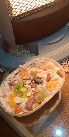 a bowl filled with fruit sitting on top of a table next to a toaster oven