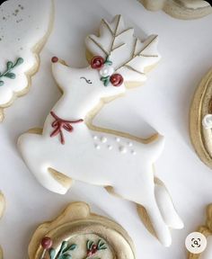 decorated cookies and pastries are arranged on a white tablecloth with gold trimmings