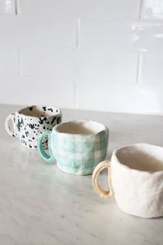 three ceramic cups sitting on top of a counter