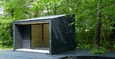 an outhouse in the middle of a wooded area with trees and water around it