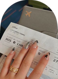 a woman's manicured nails with gold and silver designs on them, next to an airplane ticket