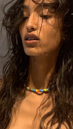 a close up of a woman with long hair wearing a beaded necklace on her neck