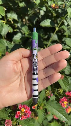 a hand holding a purple and green pen with a skeleton on it's side