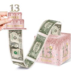 a birthday cake made out of money is being held by a hand with the number thirteen on it