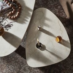 two tables with rings and beads on them sitting on the floor next to each other