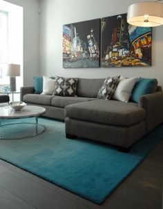 a living room with two paintings on the wall and a blue rug in front of it