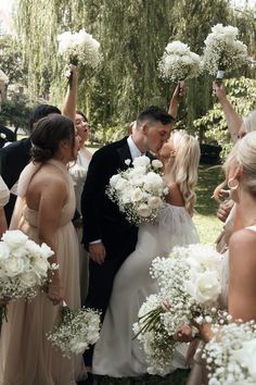 a bride and groom kissing in front of their wedding party