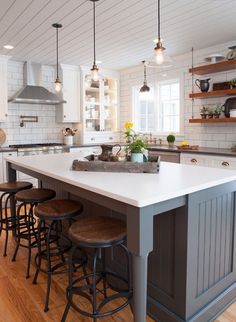 a kitchen island with four stools in front of it