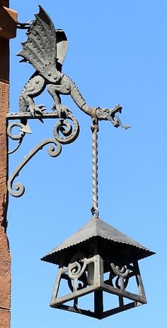 an old fashioned clock on the side of a building with a bird decoration hanging off it's side