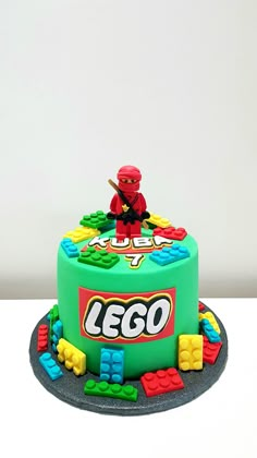 a green lego cake with a red man on top and yellow blocks around the base