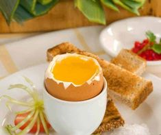 an egg is sitting in the middle of toast on a plate next to strawberries