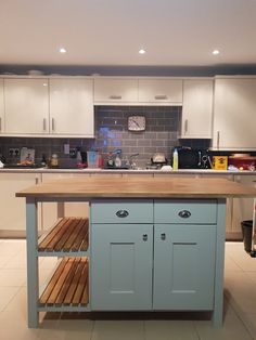 a kitchen with white cabinets and wooden counter tops