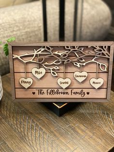 a wooden family tree with hearts hanging from it's sides on top of a table