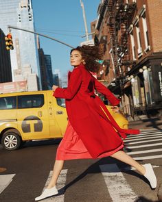 a woman in a red coat crossing the street