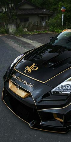 a black and gold sports car parked on the side of the road in front of a house