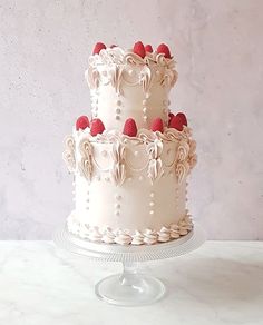 two tiered cake with white frosting and raspberries on the top layer