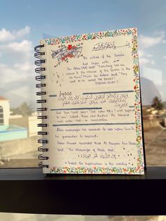 an open notebook sitting on top of a window sill next to a building and blue sky