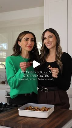 two women standing next to each other in a kitchen with food on the counter top