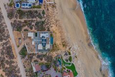 an aerial view of a beachfront home near the ocean with blue water and sand