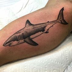 a man's arm with a black and white tattoo of a shark on it