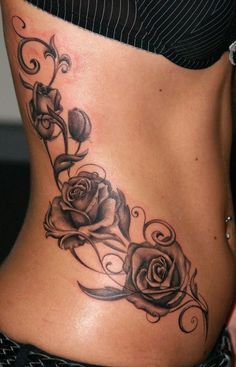 black and white photo of a woman's stomach with roses on the side tattoo