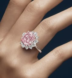 a woman's hand with a pink and white diamond ring on top of it