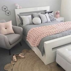 a bedroom with a bed, chair and rug in the middle of it on carpeted flooring