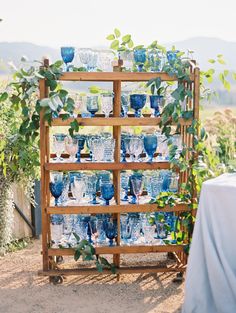 an instagram photo with blue glassware on display in front of a wooden rack