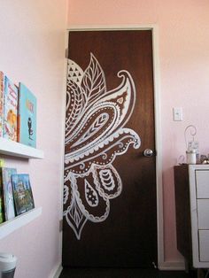 a wooden door with an intricate design painted on it in a pink room next to a white dresser