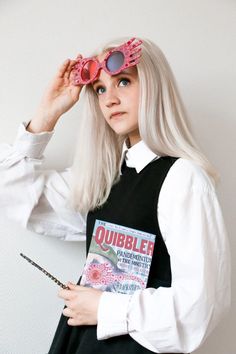 a woman with long blonde hair and pink glasses is holding a magazine in her hands