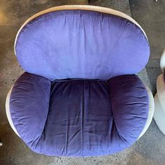 a purple chair sitting on top of a cement floor next to a white chair and ottoman