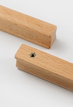 two pieces of wood sitting next to each other on a white surface with one piece missing