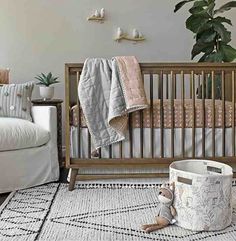 a baby's room with a crib, chair and blanket on the floor