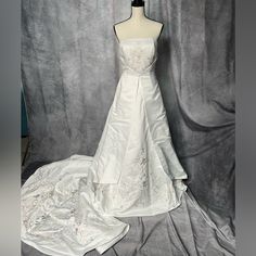 a white wedding dress on display in front of a gray backdrop