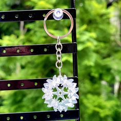 a close up of a key chain with a snowflake design on it and trees in the background